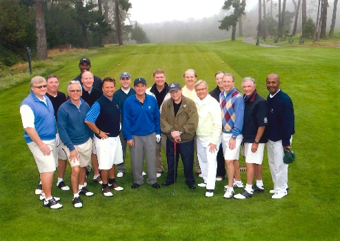 Michael Neidorff on a golf course posing with about a dozen men